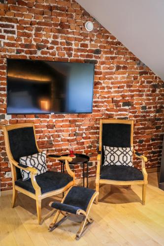 two chairs in front of a brick wall with a tv at LA GLORIETTE in Marche-en-Famenne