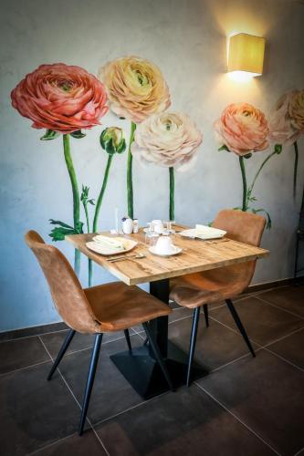 a table with chairs and flowers on the wall at LA GLORIETTE in Marche-en-Famenne