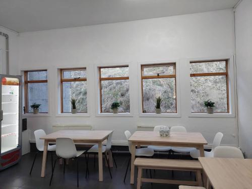 a dining room with tables and chairs and windows at Bergistangi Hostel in Norðurfjörður