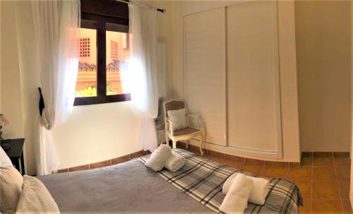 a bedroom with a bed and a window and a chair at Deluxe 2 bedroom Golf Apartment Puerto Banus Marbella 12 Minutes Away by G00gIeMaps in Estepona