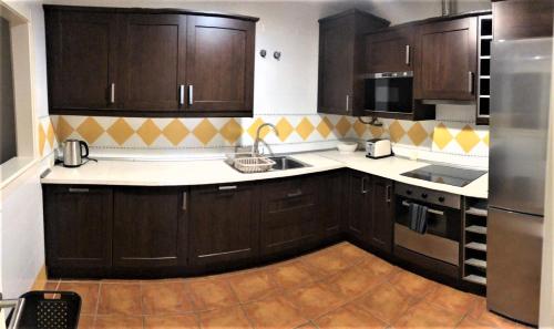 a large kitchen with wooden cabinets and stainless steel appliances at Deluxe 2 bedroom Golf Apartment Puerto Banus Marbella 12 Minutes Away by G00gIeMaps in Estepona