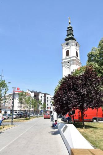 a building with a clock tower in the middle of a street at Frajla in Novi Sad