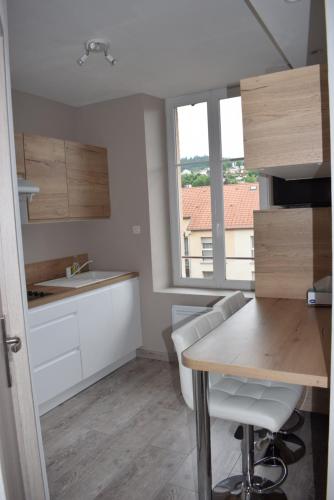 a kitchen with white cabinets and a table and a window at Superbe T3 classé 3 étoiles Chez Cathy et Frank situé en plein centre de Gérardmer in Gérardmer