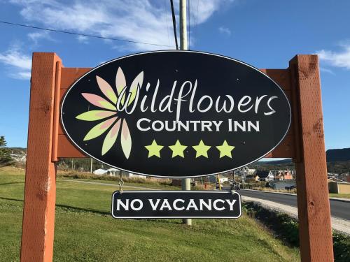 a sign for a wild flowers country inn with a no vacancy sign at Wildflowers Country Inn in Rocky Harbour