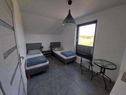 a bedroom with two beds and a table and a window at Słoneczny Zakątek Sominy in Sominy