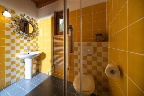 a yellow tiled bathroom with a sink and a toilet at Apartment Villa Ema in Krapinske Toplice