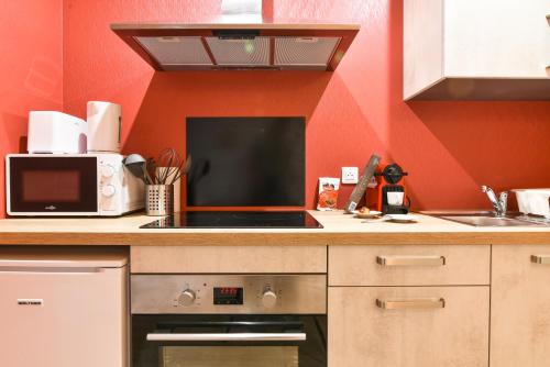 - une cuisine avec des murs rouges et une cuisinière four supérieur dans l'établissement Sauna - Le 65 Degrés - Gare, à Saverne