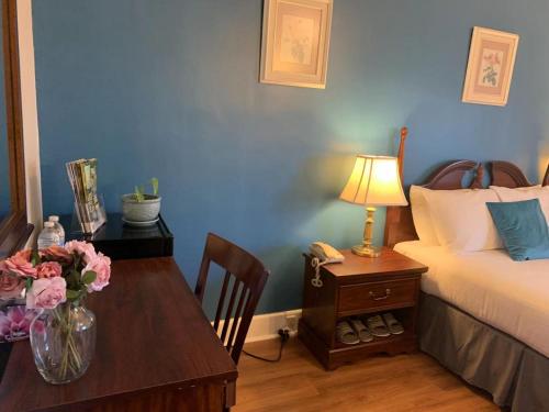 a bedroom with a bed and a table with flowers on it at Braeside Country Inn in Pictou