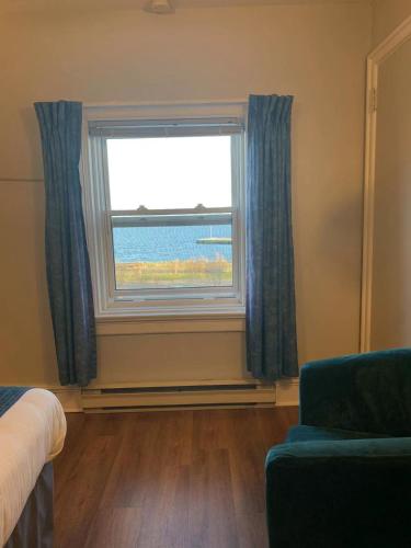 a room with a window with a couch and a chair at Braeside Country Inn in Pictou