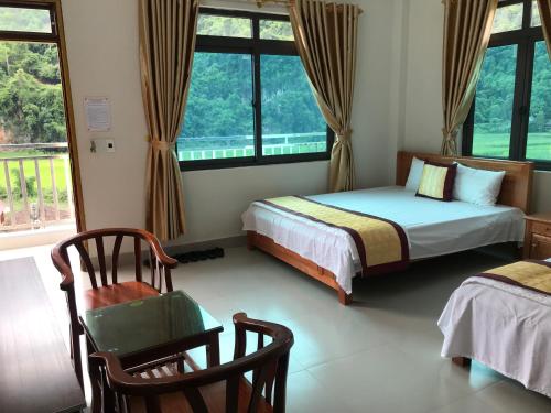 a bedroom with two beds and a chair and windows at Nha nghi PAC NGOI in Bak Kan