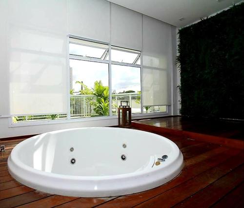 a large white bath tub in a room with a large window at Apartamento inteiro para hospedagem in Sao Paulo