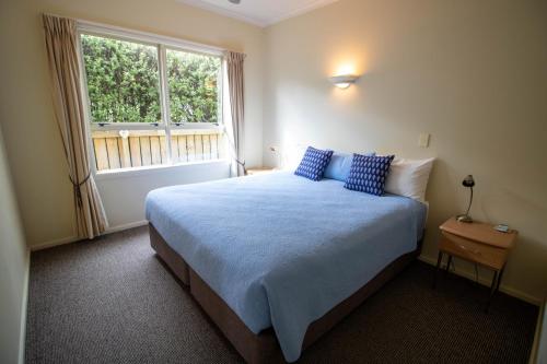 Un dormitorio con una cama con almohadas azules y una ventana en Tuscany On Thames en Thames