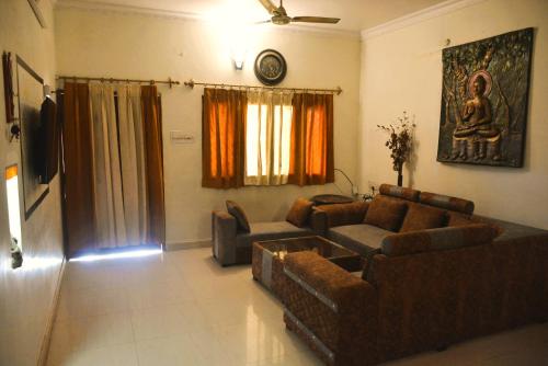 a living room with two couches and a sitting room with a statue at Malaiya Homestay - Grandeur Living Experience in Jabalpur