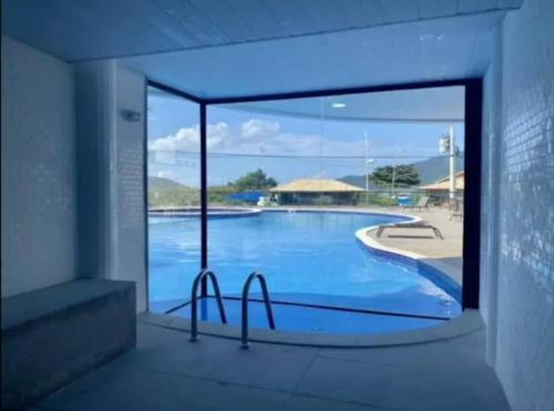 Una vista de una piscina a través de una ventana. en Apê dos Anjos, en Arraial do Cabo