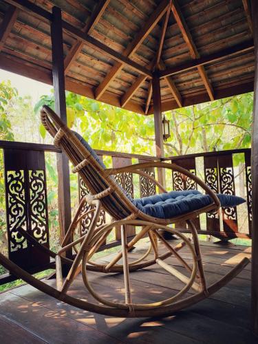 a wicker rocking chair sitting on a porch at La Maison - Chiangmai in Mae Taeng
