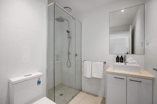 baño blanco con ducha y lavamanos en Wattle Beachside Apartment, en McCrae