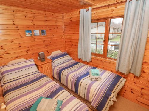 2 Betten in einem Blockhaus mit Fenster in der Unterkunft Heritage Park in Narberth