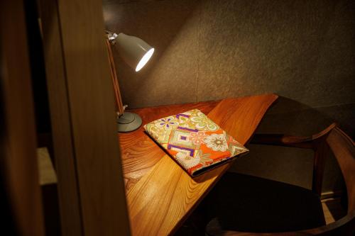 a wooden table with a lamp and a book on it at Hotel Kanazawa Zoushi in Kanazawa