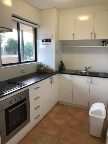 a kitchen with white cabinets and a sink at Apt 42 Riverview Holiday Apartments in Kalbarri