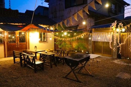 a patio with tables and chairs and lights at night at Kominka Wagaya in Higashi-osaka