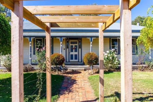 a wooden pergola in front of a house at Pound Hill Cottage in Miners Rest