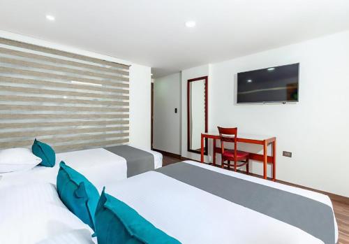 a bedroom with two beds and a table with a chair at Hotel Basan Plaza in Pasto