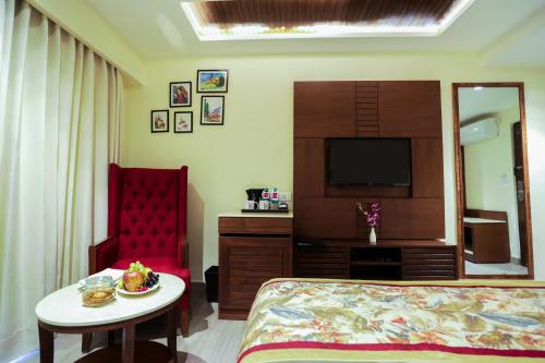 a bedroom with a bed and a table and a chair at Regenta Hilltop Shimla in Shimla