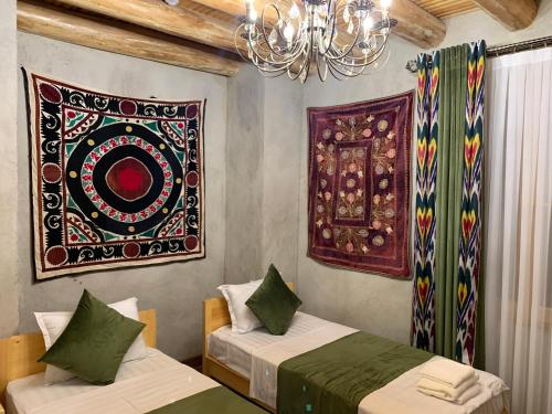 Una habitación con dos camas y un cuadro en la pared. en Shohnishin Boutique, en Bukhara