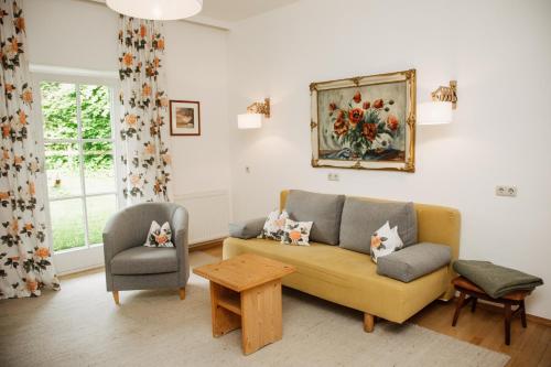 a living room with a yellow couch and a chair at Bio-Landpension Monika in Leutasch