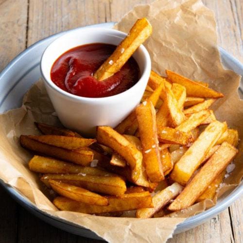a plate of french fries with a bowl of ketchup at Gandhara castle hotel Resort & Adventure Club in Khanpur