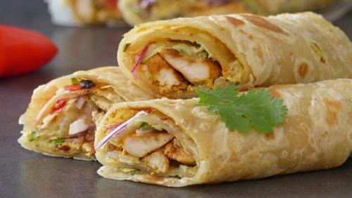 a wrap with chicken and vegetables on a table at Gandhara castle hotel Resort & Adventure Club in Khanpur
