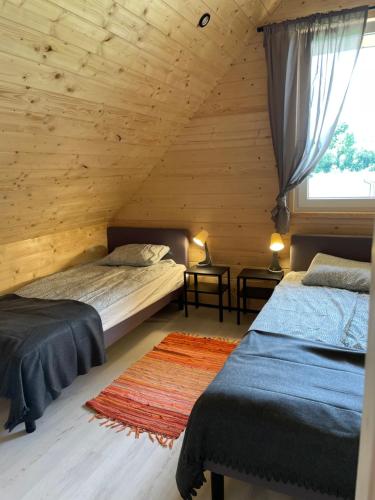 two beds in a room with wooden walls at Domki Rózin in Zwierzyniec