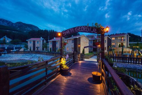 a building with a sign on a wooden bridge at Ethno Village St George in Cetinje