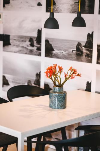 a white table with a vase with orange flowers on it at One Suite Hotel in Mlini