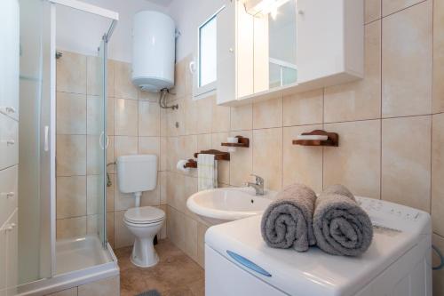 a white bathroom with a sink and a toilet at Apartment Lazić Pag by Pag tours in Pag