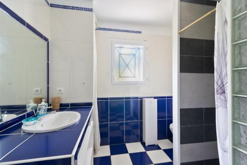 La salle de bains bleue et blanche est pourvue d'un lavabo et d'un miroir. dans l'établissement Biarritz 64 Road House, à Arbonne
