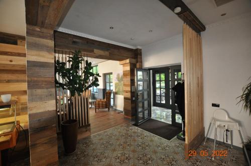 a living room with a hallway with wooden walls and a plant at Parkhotel Schwedt in Schwedt