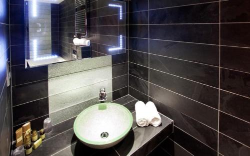 a black tiled bathroom with a sink and a mirror at Applegarth Villa Hotel & Restaurant (Adult Only) in Windermere