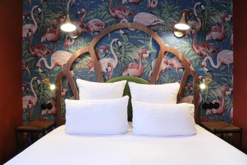 un letto con cuscini bianchi e carta da parati con fenicotteri di Hotel André Latin a Parigi