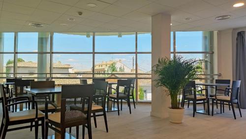 ein Restaurant mit Tischen und Stühlen und großen Fenstern in der Unterkunft Smart Hotel La Sagra in Yuncos