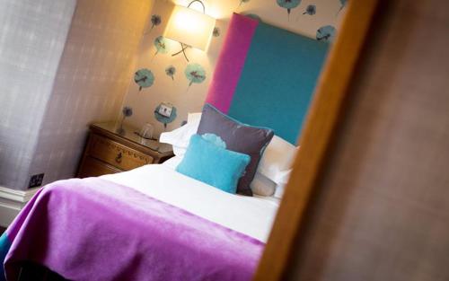 a bedroom with a bed with a pink and blue headboard at Applegarth Villa Hotel & Restaurant (Adult Only) in Windermere