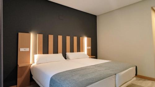 ein Schlafzimmer mit einem großen weißen Bett und einer schwarzen Wand in der Unterkunft Smart Hotel La Sagra in Yuncos