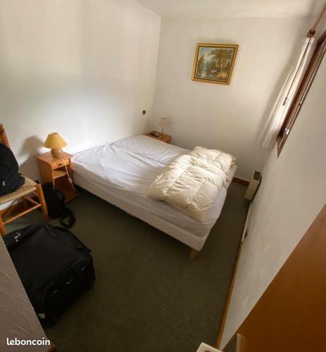 - une petite chambre avec un lit et une valise dans l'établissement Le Clos d'Arly, à Praz-sur-Arly
