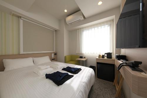 a bedroom with a bed with two towels on it at Fourz Hotel Kintetsu Osaka-Namba in Osaka