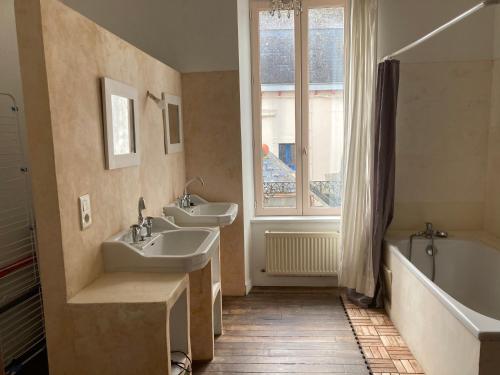 ドゥアルヌネにあるT2 Quartier du Rosmeurのバスルーム(洗面台2台、バスタブ付)、窓が備わります。