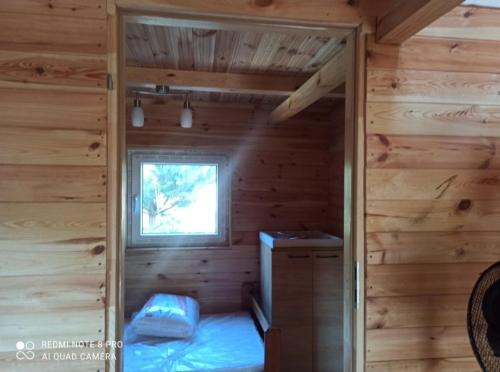 una camera in una baita di tronchi con un letto e una finestra di Domki letniskowe a Jedlinsk