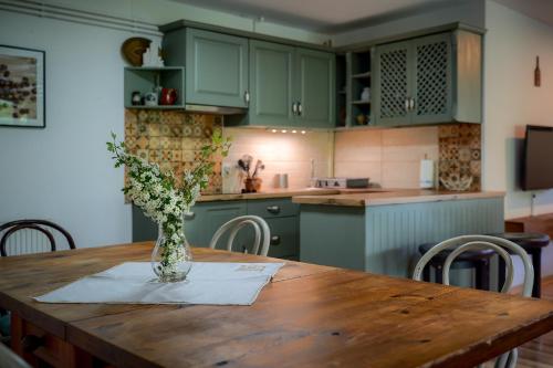 a kitchen with a wooden table with a vase of flowers on it at Parkside Vila in Odorheiu Secuiesc