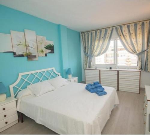 a blue bedroom with a white bed and a window at La duquesa in Fuengirola