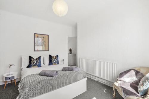 Stunning Victorian property near Canary Wharf! في لندن: غرفة نوم بيضاء بسرير وكرسي