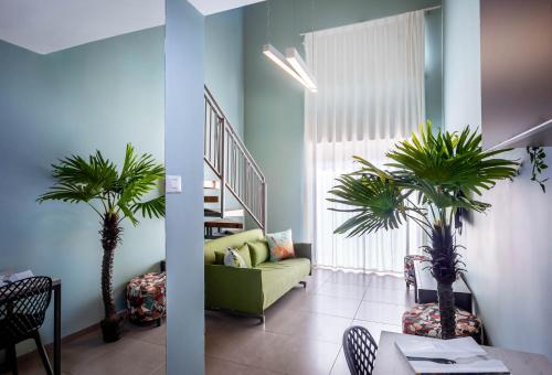 a living room with a green couch and two palm trees at Almogim Suites Eilat Hotel in Eilat